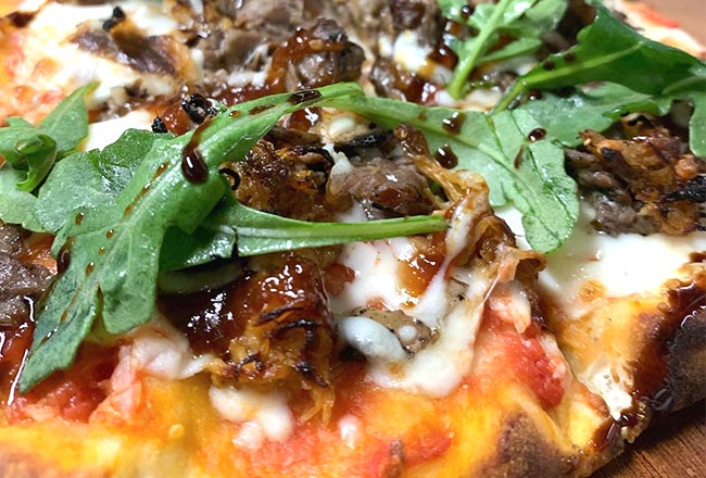 Flatbread with braised beef, blue cheese, tomato and arugula